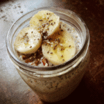 A bowl of overnight oats with banana and chia seeds, topped with fresh fruit and nuts.
