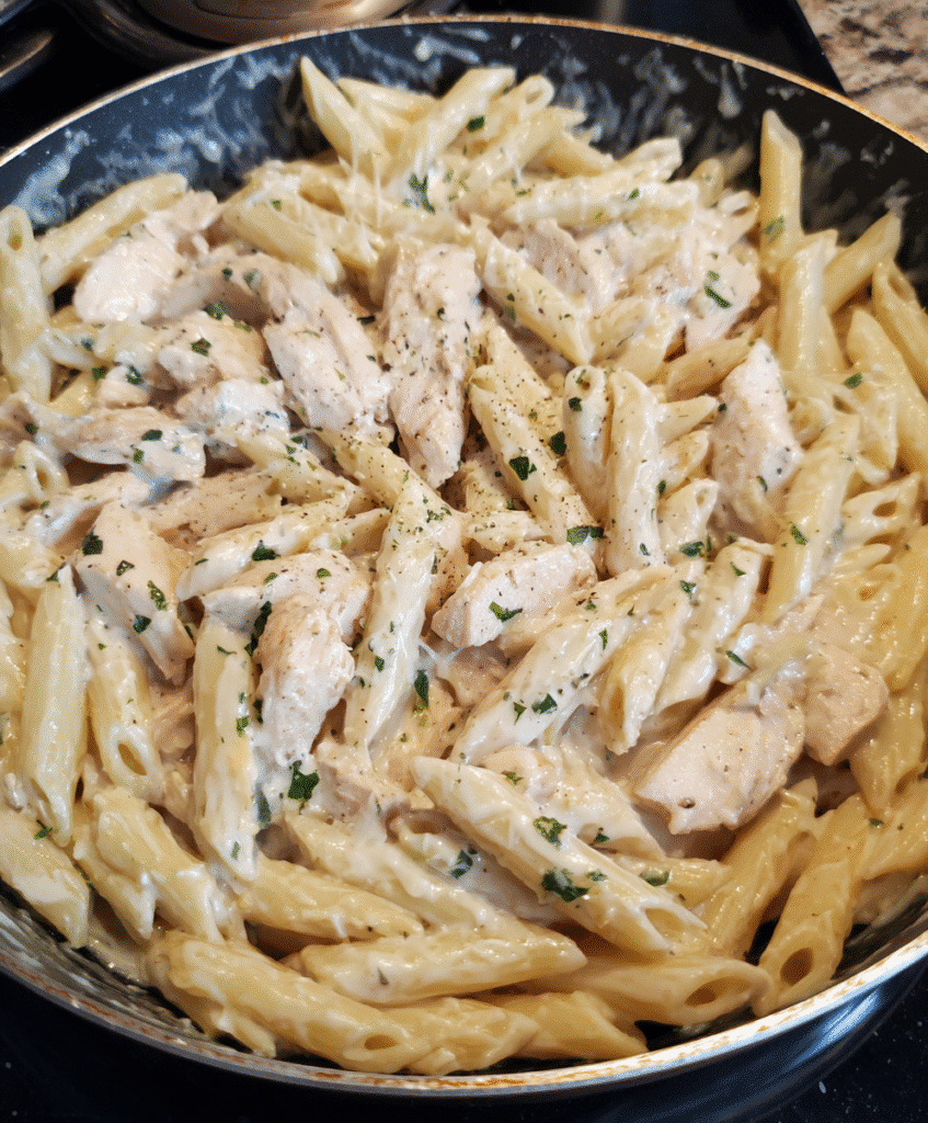Easy Chicken Alfredo Penne Pasta served in a bowl with creamy sauce and fresh parsley garnish.
