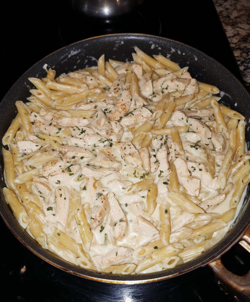 Chicken pieces cooking in a skillet for Chicken Alfredo Penne Pasta.