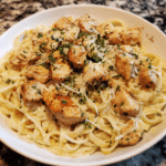 Garlic butter chicken bites with creamy Parmesan pasta, garnished with parsley.