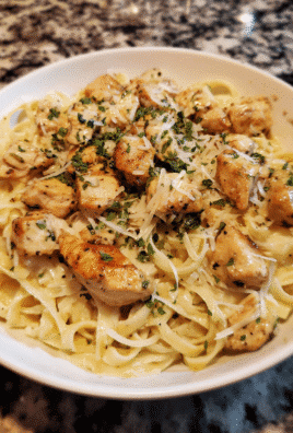 Garlic butter chicken bites with creamy Parmesan pasta, garnished with parsley.