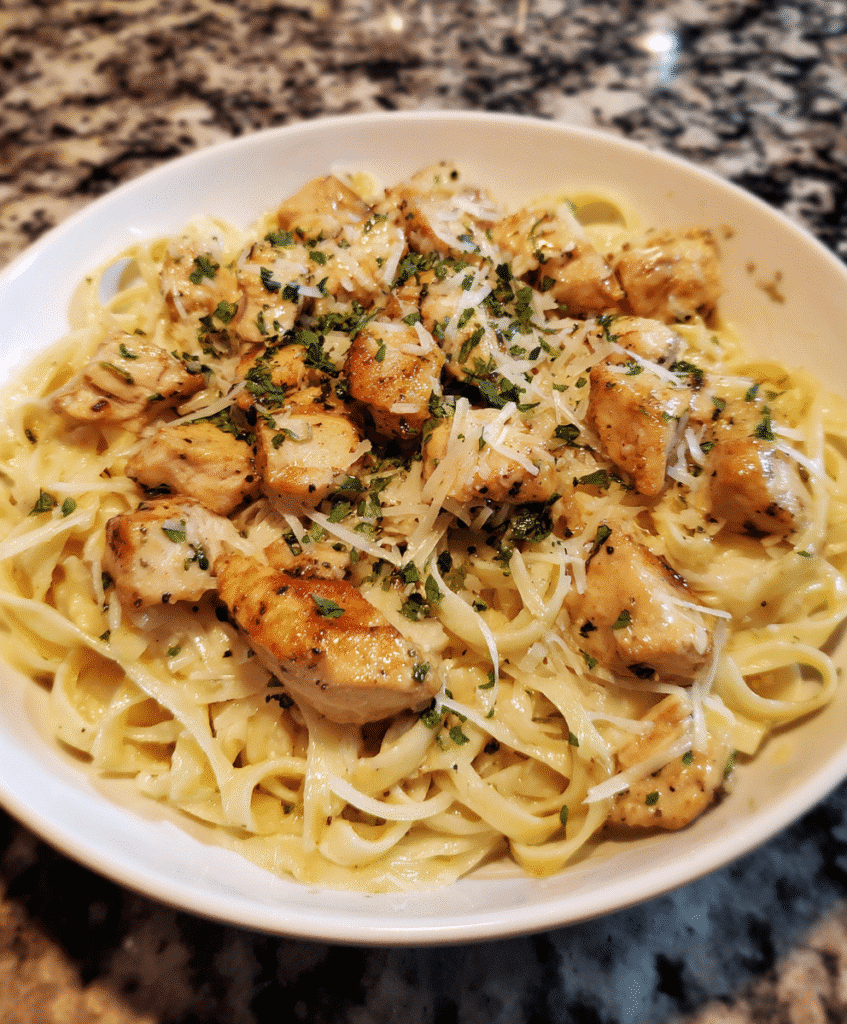 Garlic butter chicken bites with creamy Parmesan pasta, garnished with parsley.