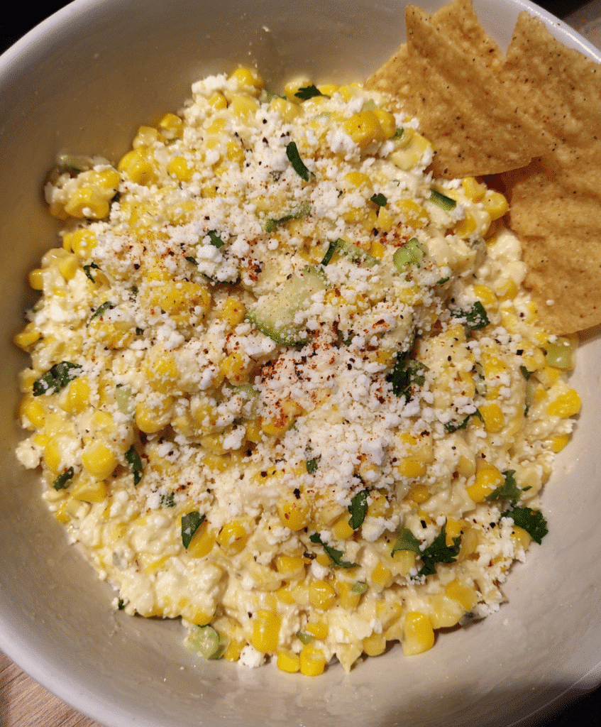 Bowl of Mexican Street Corn Dip with tortilla chips and fresh veggies for dipping